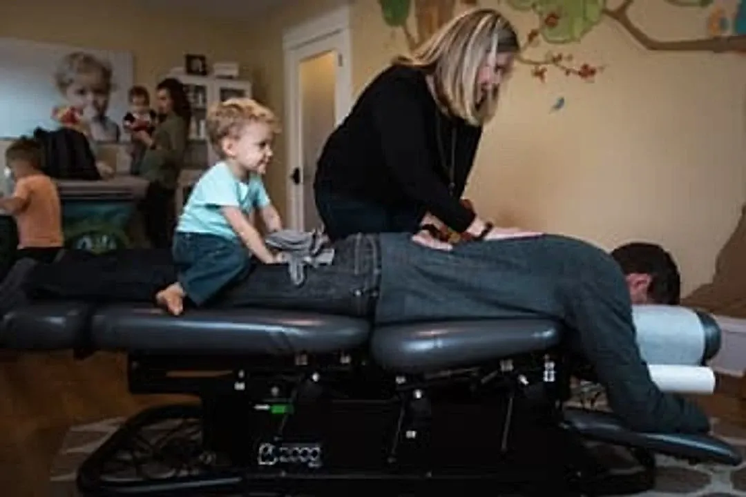 A child sits on a parent on the adjusting table